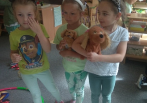 Trzy dziewczynki stoją, mają na głowach opaski z uszami zwierzątek