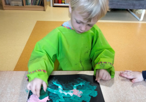 dziecko stempluje gąbką umoczoną w farbie sylwetę krokodyla
