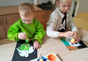 dzieci stemplują gąbką umoczoną w farbie sylwety zwierząt