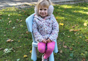 dziewczynka siedzi w ogrodzie na rzesełku