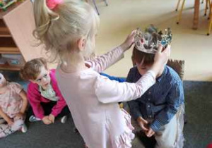 Dziewczynka zakłada na głowę jubilata koronę