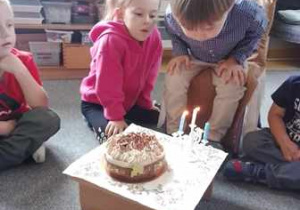 Jubilat zdmuchuje świeczki z urodzinowego tortu