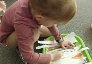 Dziewczynka maluje pień brzozy przy użyciu kredki pastelowej