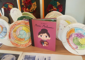 Zdjęcie przedstawia książkę Maria Montessori i ślimaki wykonane przez dzieci z talerzyków papierowych