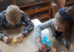 Chłopiec z dziewczynką siedzą przy stoliku i ozdabiają kolorowe puzzle