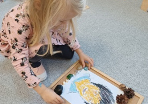 Dziewczynka układa portret Marii Montessori na korkowej podkładce