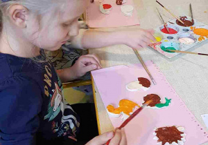 Dziewczynka maluje farbami figurki z masy solnej
