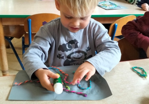 chłopiec tworzy abstrakcję z włóczki