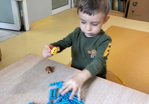 chłopiec tworzy konstrukcję z klocków