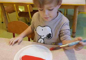 Chłopiec maluje papierowy talerzyk