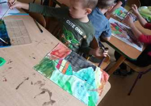 Chłopiec nabiera farbę akwarelową na pędzel w czasie wykonywania pracy plastycznej