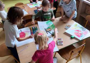 Dzieci starsze w czasie wykonywania pracy plastycznej - malowanie jesiennego liścia według własnego pomysłu
