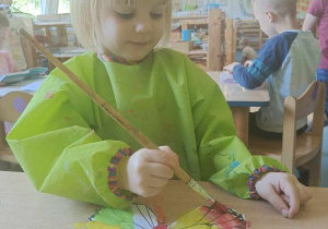 Dziewczynka maluje motyla farbami