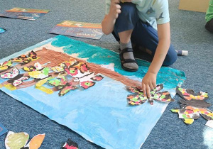 Chłopiec układa motyle na malowanym przez siebie tle