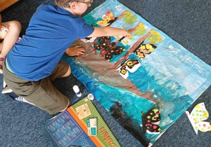 Chłopiec układa motyle na malowanym przez siebie tle