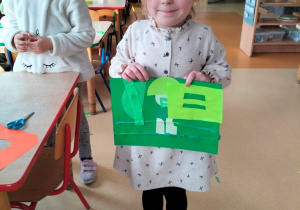 dziewczynka prezentuje swoją pracę w odcienaich koloru zielonego