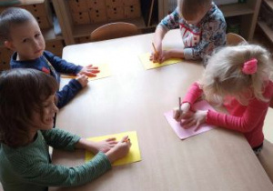 Dzieci na kolorowym papierze odrysowują swoją dłoń