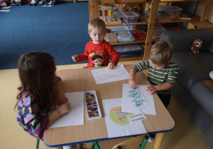 Troje dzieci siedzi przy stoliku i ilustruje wybrane prawo dziecka