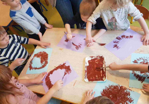 Dzieci stemplują widelcem umoczonym w brązowej farbie