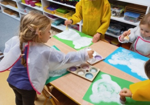 Dzieci stemplują białego misia farbą