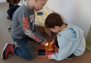 Dzieci oglądają kolorowe witraże w świetle latarki