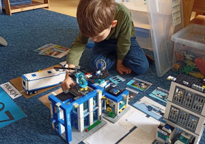 Chłopiec układa makietę Policja z klocków Lego
