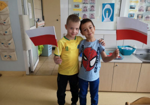 Dwóch chłopców pozuje do zdjęcia trzymając w rękach flagi