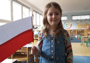Dziewczynka pozuje z wykonaną przez siebie flagą