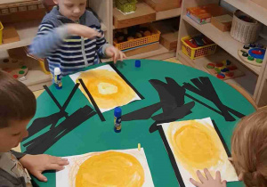 Dzieci malują tło pracy plastycznej i przyklejają paski