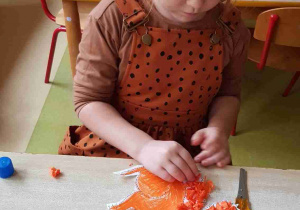 Dziewczynka wykleja ogon wiewiórki przy użyciu pomarańczowej bibuły