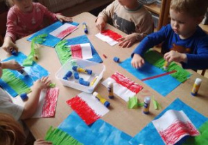 Dzieci przyklejają poszczególne elementy flagi