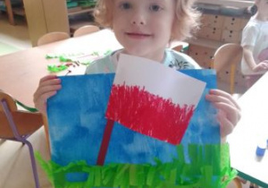Tadzio prezentuje flagę Polski powiewajacą na niebieskim tle