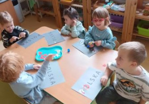 Dzieci wyklejają napis Polska biało-czerwonymi elementami