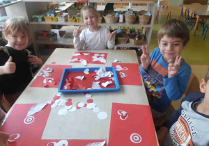 Dzieci siedzą przy stole i wykonują prace plastyczne