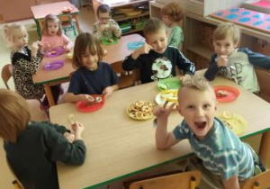 Dzieci z uśmiechami na twarzach jedzą owoce