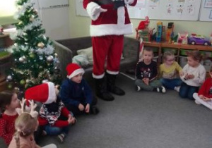Mikołaj rozmawia z dziećmi, które siedzą w kręgu na dywanie