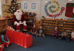 Mikołaj siedzi na krześle i jest gotowy do rozdawania prezentów dzieciom