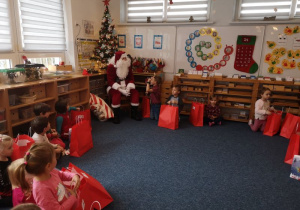 Mikołaj siedzi na krześle i rozmawia z dziećmi
