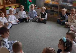 Dzieci siedzą w kręgu w oczekiwaniu na Uroczystość Wigilijną