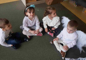 Dzieci siedzą na dywanie w oczekiwaniu na Uroczystość Wigilijną