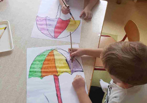 Dzieci malują farbami plakatowymi papierowe parasole