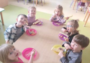 Dzieci w wesołym nastroju jedzą tort urodzinowy
