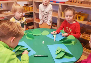Dzieci składają choinkę z zielonych kół origami