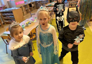 Zdjęcie przedstawia dwie dziewczynki przebrane za księżniczki oraz chłopca przebranego za "Batmana"