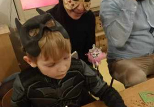 Brunon wraz z mamą ozdabia maskę karnawałową brokatem