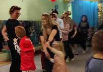 Dzieci tańczą wraz z rodzicami podczas balu karnawałowego