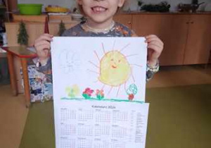 Dziewczynka trzyma w dłoniach zrobiony przez siebie kalendarz
