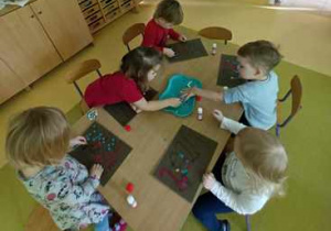Dzieci młodsze przy stoliku w czacie wykonywania pracy plastycznej