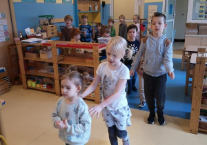 Dzieci podczas zabawy ruchowej poruszają się w pociągu, jedno za drugim po sali