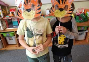 Chłopcy chowają się za swoimi maskami przedstawiającymi tygrysa